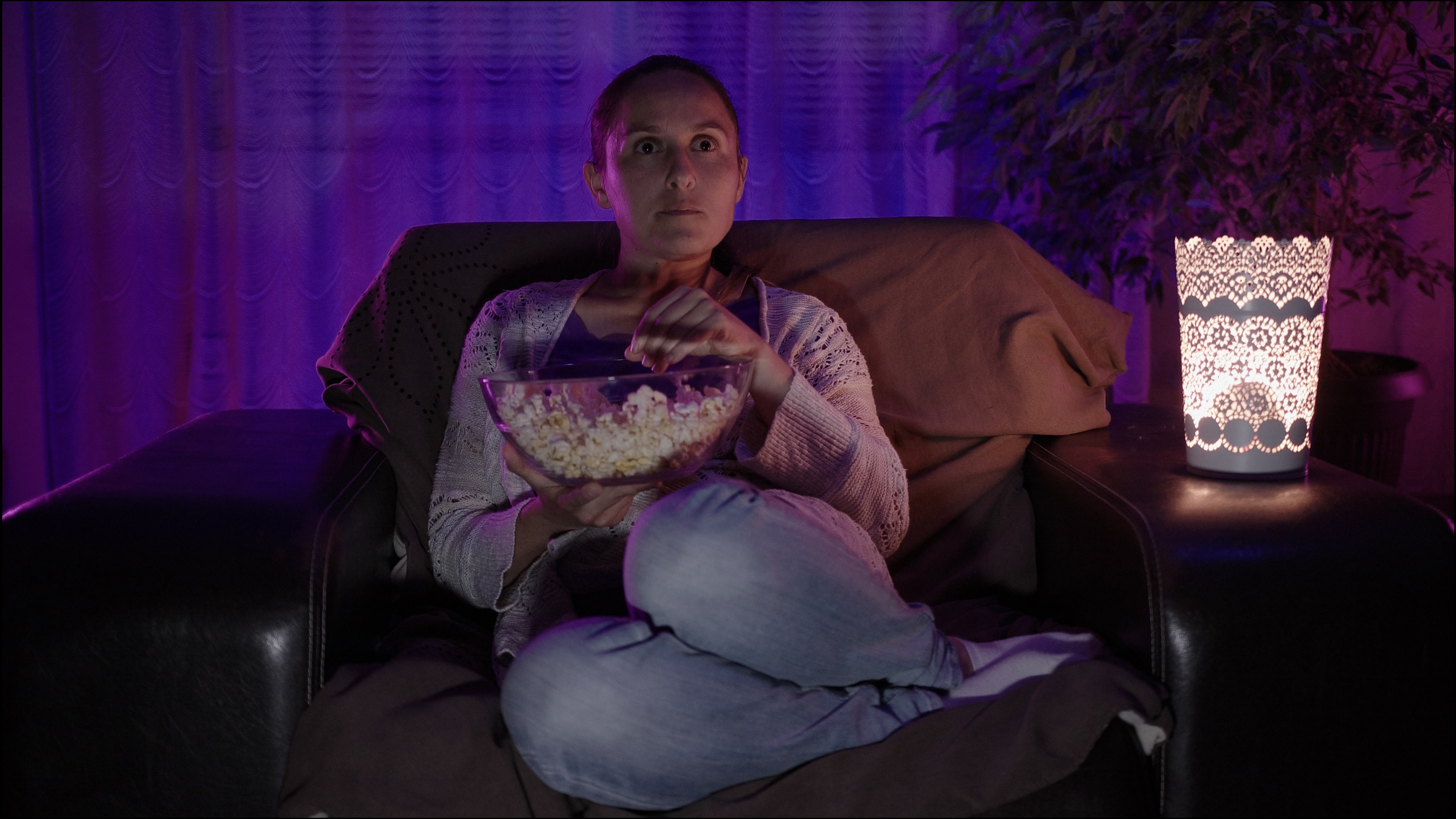 Woman relaxing at home with popcorn in front of the TV.